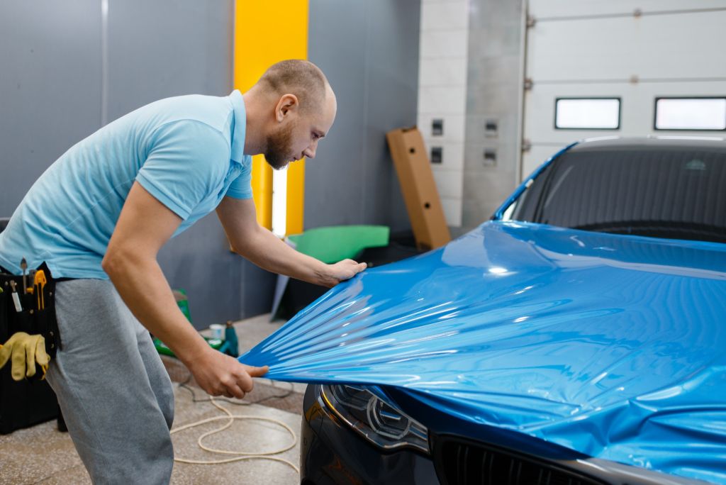 Car wrapper puts protective foil or film on hood
